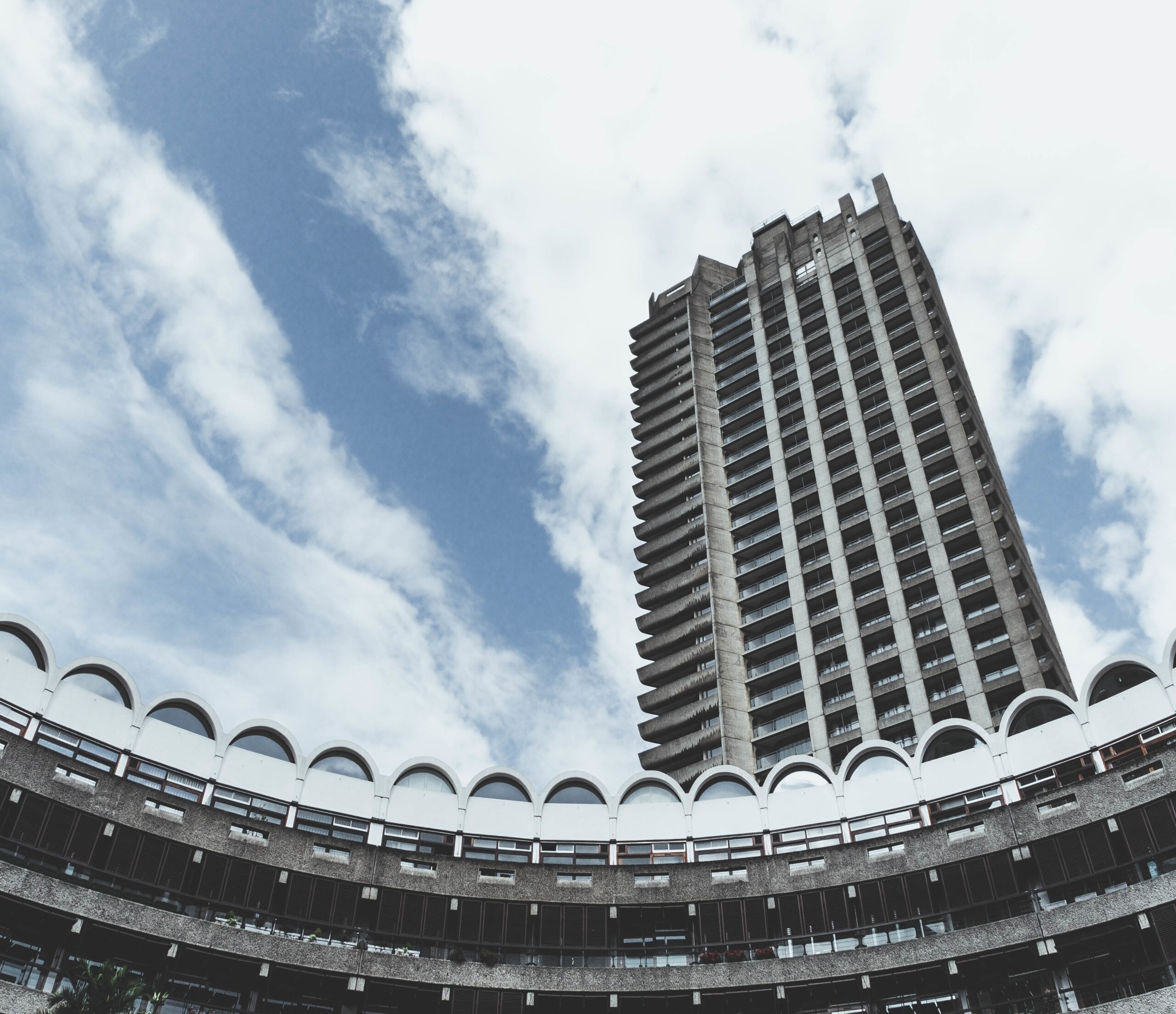 low angle shot of barbican centre in london with a cloudy blue sky in the background
